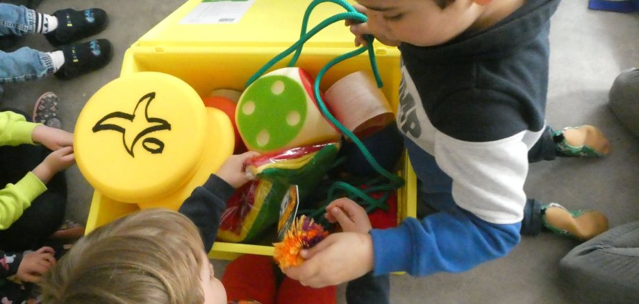 Kinder schauen sich die Materialien in der "move it"-Box an.