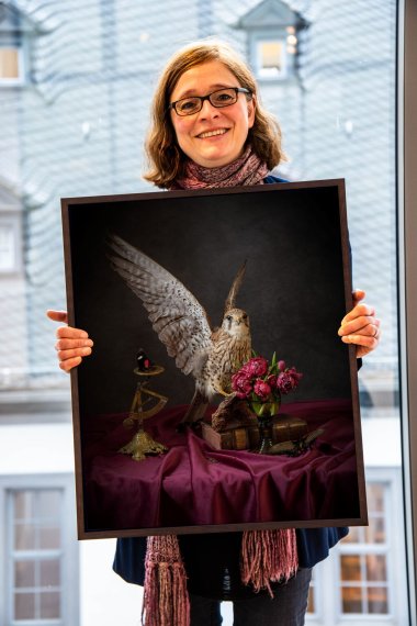 Elizabeth Joan Clarke fotografiert Stillleben. Dieses Bild trägt den Titel "Flight". Es handelt von Flucht, erläutert die Künstlerin. Das Foto zeigt die Künstlerin, wie sie eines ihrer Werke in den Händen hält.