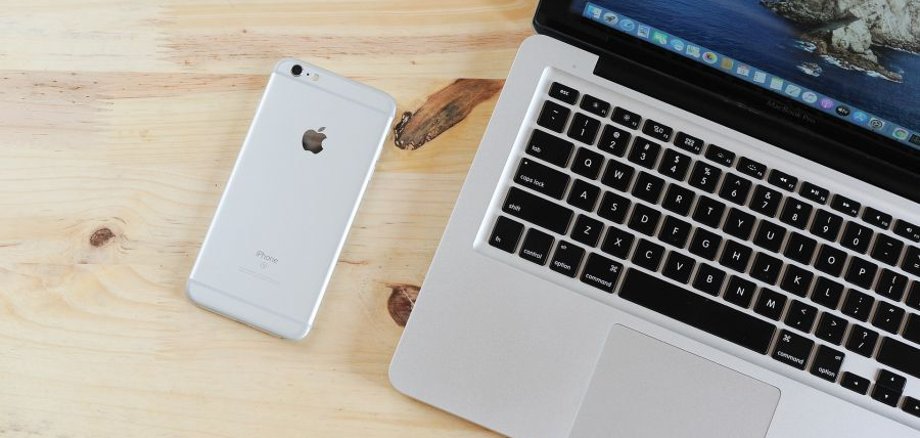 Das Foto zeigt ein Laptop und ein iPhone auf einem Tisch.