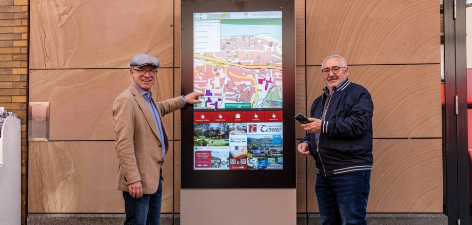 Boppards Bürgermeister Jörg Haseneier (links) und Kommunalberater Werner Bergsträßer von der Bender Verlags GmbH an der neuen digitalen Infostele vor der Boppparder Stadthalle. 