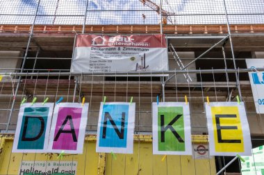 Das Foto zeigt bunte laminierte Schilder, die am Bauzaun an der Grundschule angebracht sind und das Wort "Danke" darstellen.