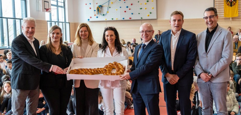 Schlüsselübergabe in der Michael-Thonet-Sporthalle. Der Architekt überreicht Bürgermeister Jörg Haseneier und der Schulleiterin Andrea Adam einen als Hefezopf gebackenen Schlüssel.