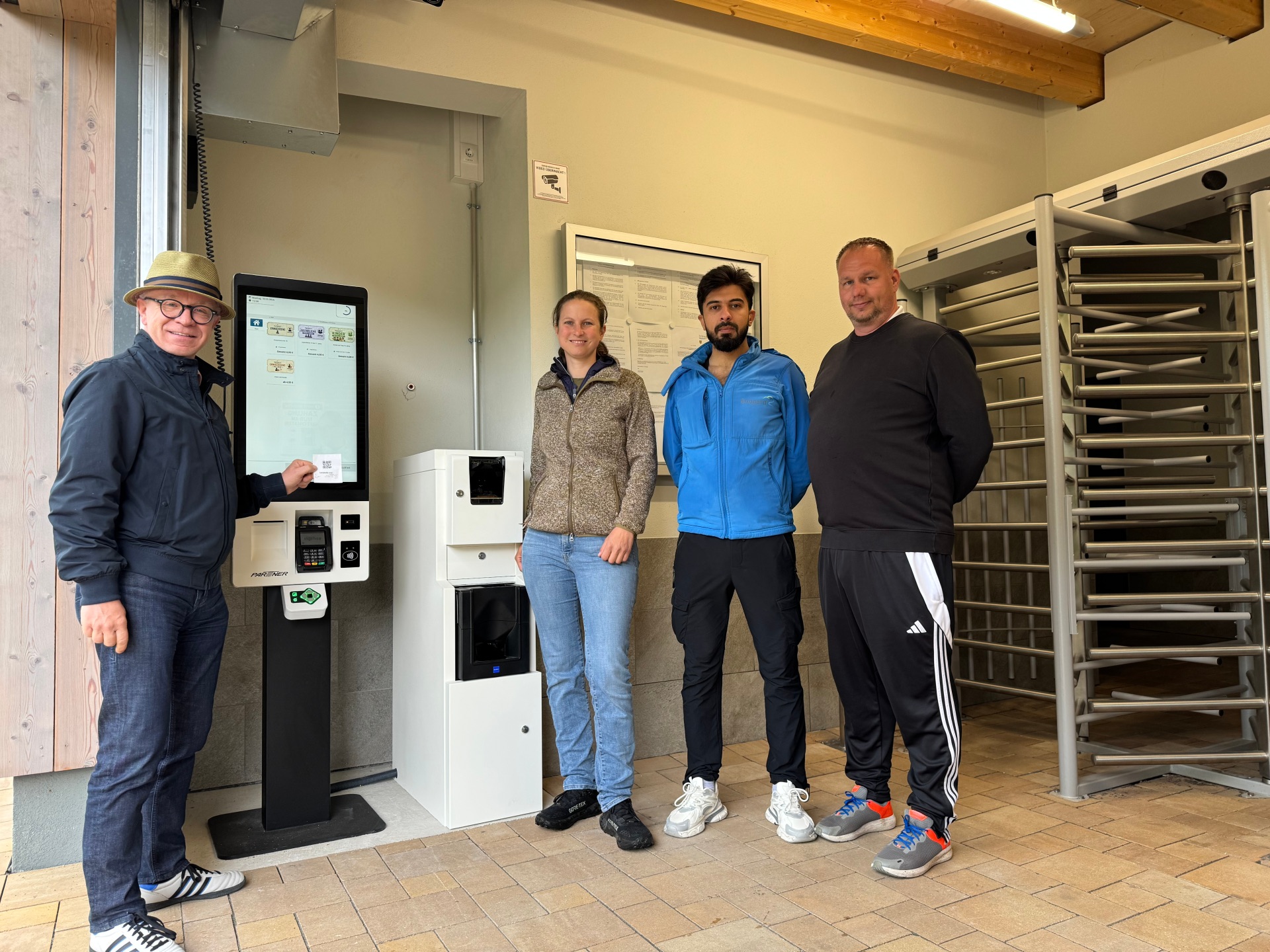 Bürgermeister Jörg Haseneier (von links) und Ortsvorsteherin Alexa Bach testeten den neuen Kassenautomaten im Thermalfreibad in Buchenau und erstanden die ersten Freibadtickets für die Saison 2026. Mit ihnen freuen sich Rettungsschwimmer Bsher Almanfi und Betriebsleiter Christian Meinecke auf zahlreiche Badegäste. 