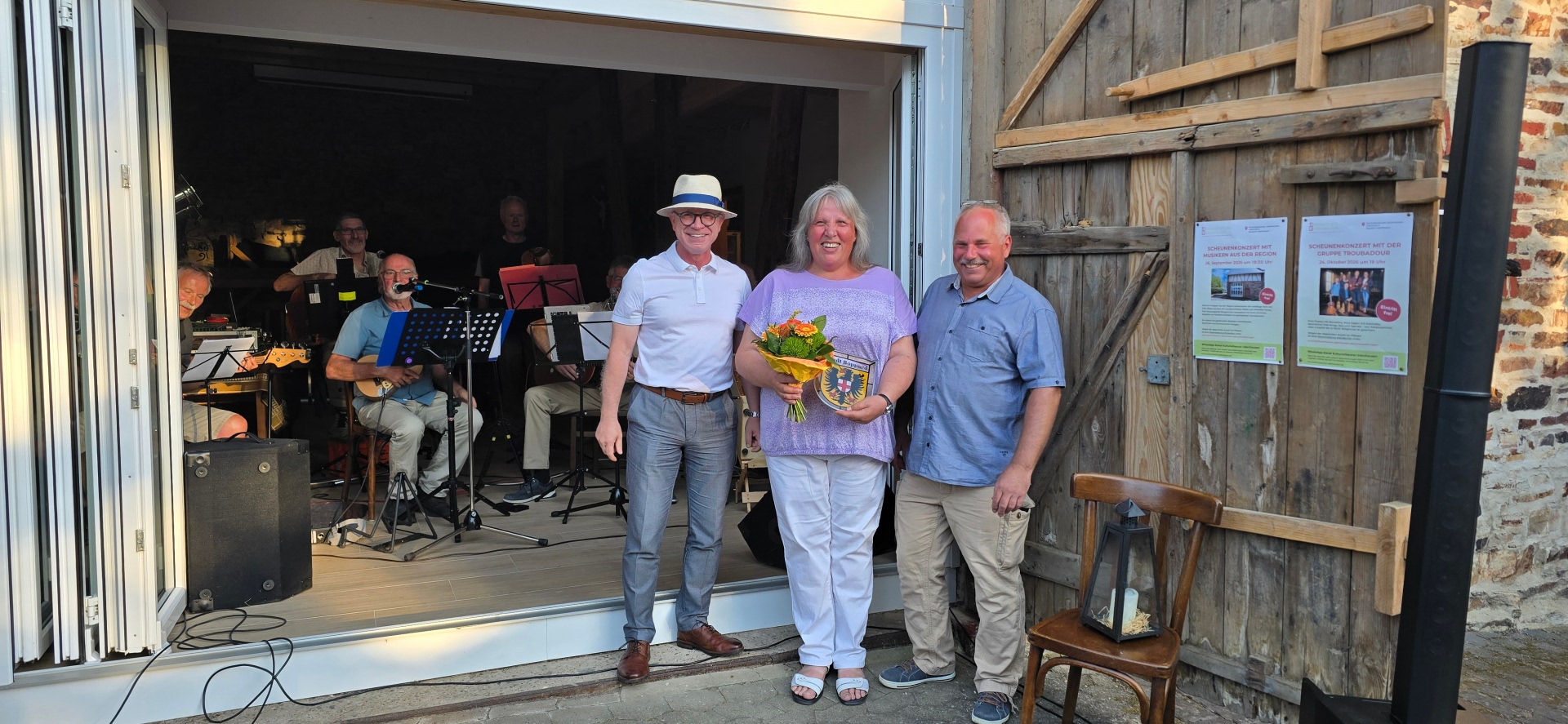 Bei der Eröffnung der Kulturscheune in Udenhausen (von links): Boppards Bürgermeister Jörg Haseneier, Barbara Vogt und Ortsvorsteher Michael Güntzel vor der Musikgruppe Hinnerschd de Veereschd. 