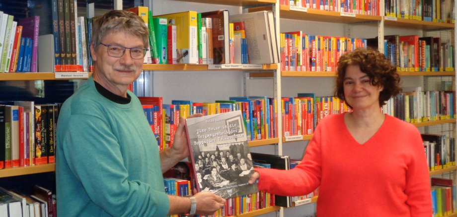 Heinz Kähne, Vorsitzender des Verkehrs- und Verschönerungs-Vereins  (VVV) überreicht ein Buchgeschenk an die Leiterin der Stadtbücherei.