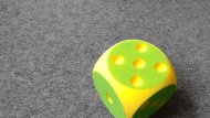 Gelb-grüner Stoffwürfel auf Filzteppichboden