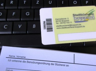 Anmeldeformular und Büchereiausweis liegen auf einer Computertastatur Anmeldeformular und Büchereiausweis liegen auf einer Computertastatur