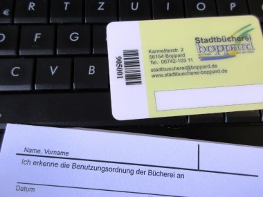 Anmeldeformular und Büchereiausweis liegen auf einer Computertastatur