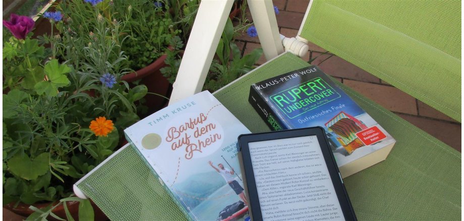 Foto: Bücher und E-Bookreader liegen auf einem Balkonstuhl