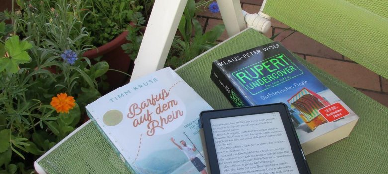 Foto: Bücher und E-Book-Reader liegen auf einem Balkonstuhl. Foto: Bücher und E-Book-Reader liegen auf einem Balkonstuhl.