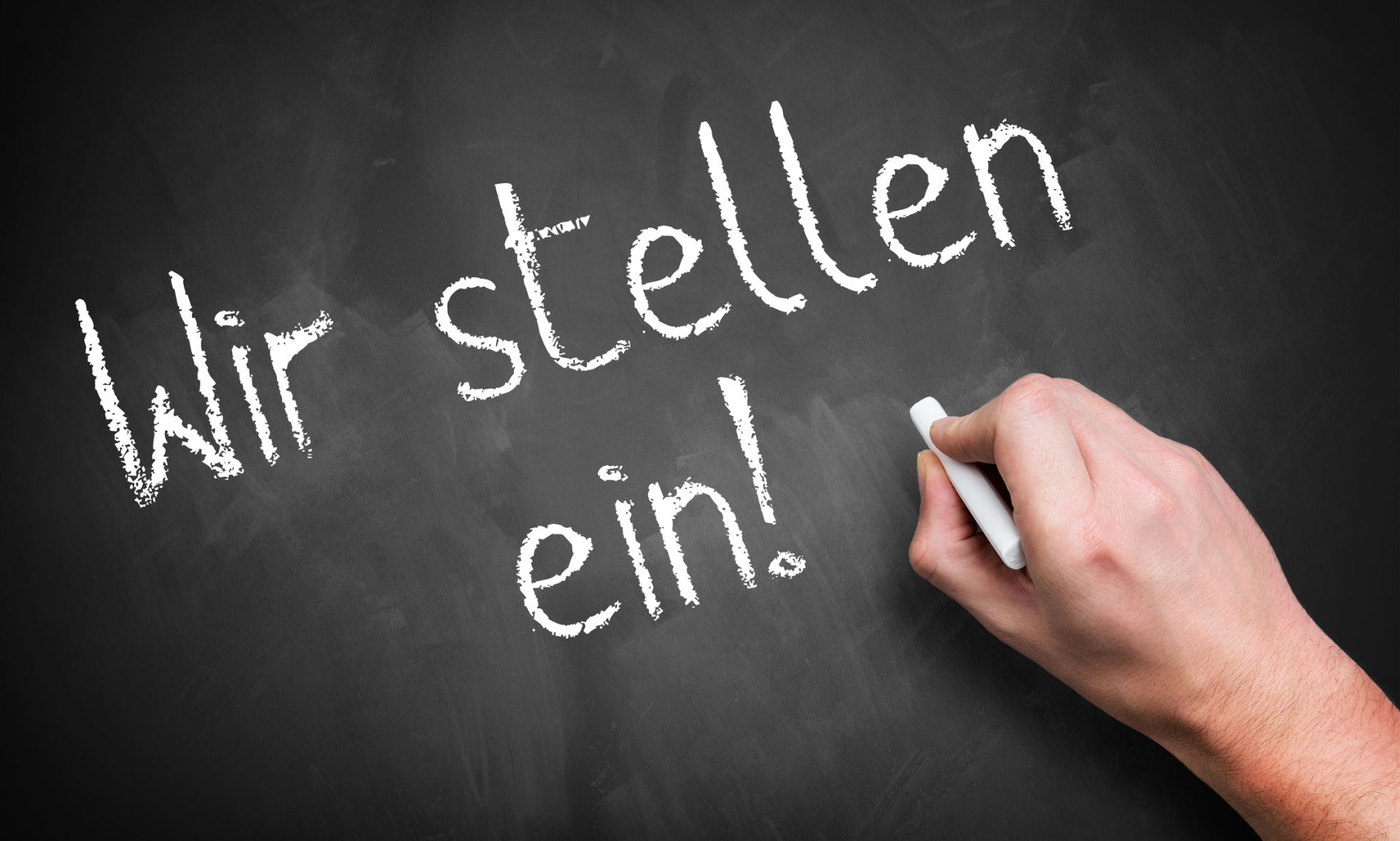 hand writing 'We are hiring!' in German on a chalkboard hand writing 'We are hiring!' in German on a chalkboard