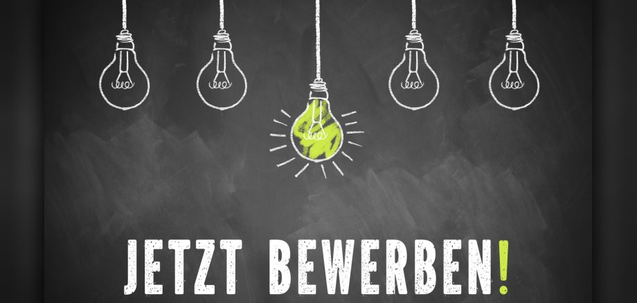 chalk lightbulbs and the message 'Apply Now!' in German on a chalkboard Jetzt bewerben