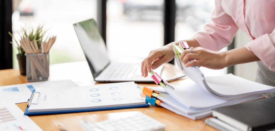 Businesswoman hands working in Stacks of paper files for searching and checking unfinished document achieves on folders papers