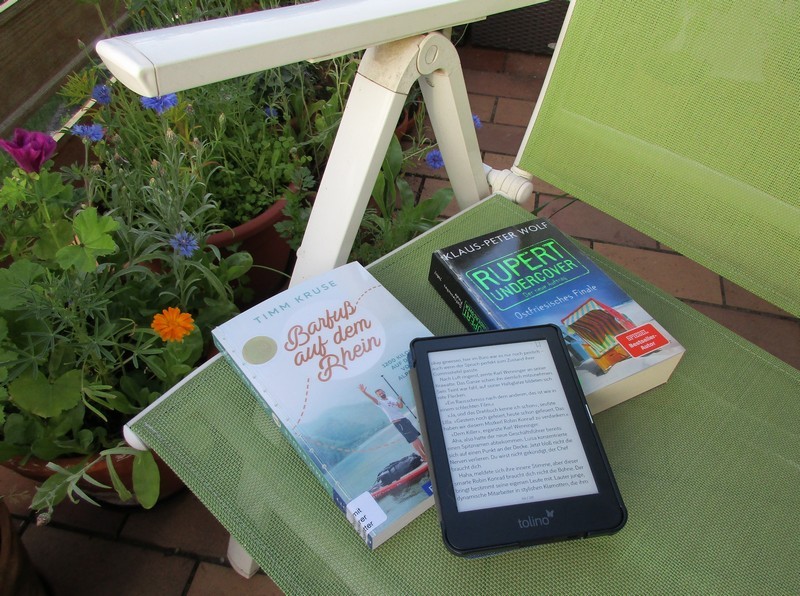 Das Foto zeigt Bücher und einen E-Book-Reader auf einem Gartenstuhl.