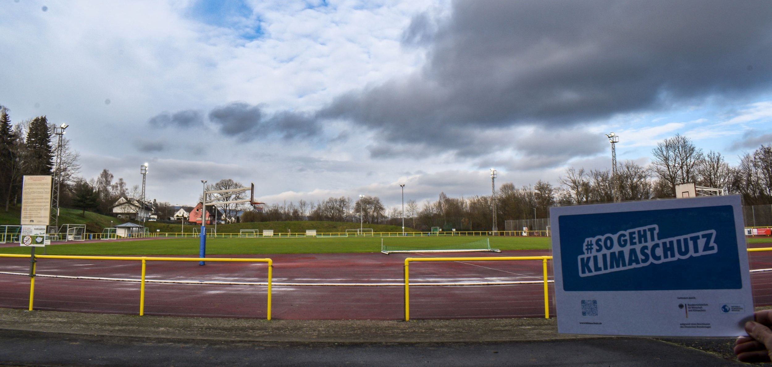 Das Foto zeigt das BOMAG-Stadion in Boppard mit den neuen Flutlichtanlagen. Im Vordergrund ein Flyer mit der Aufschrift: So geht Energiesparen.