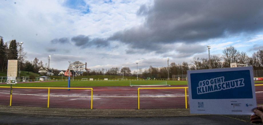 Das Foto zeigt das BOMAG-Stadion in Boppard mit den neuen Flutlichtanlagen. Im Vordergrund ein Flyer mit der Aufschrift: So geht Energiesparen.
