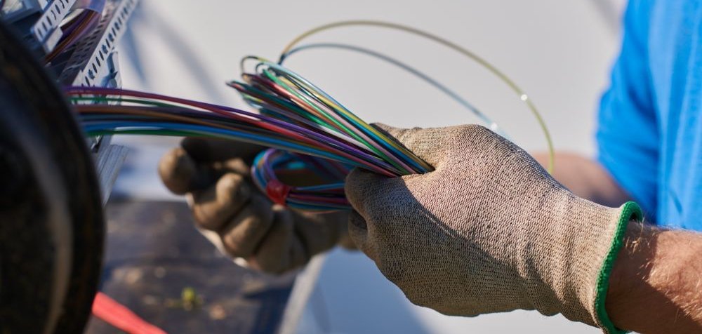 Die Hand eines Technikers hält ein Bündel Galsfaserkabel