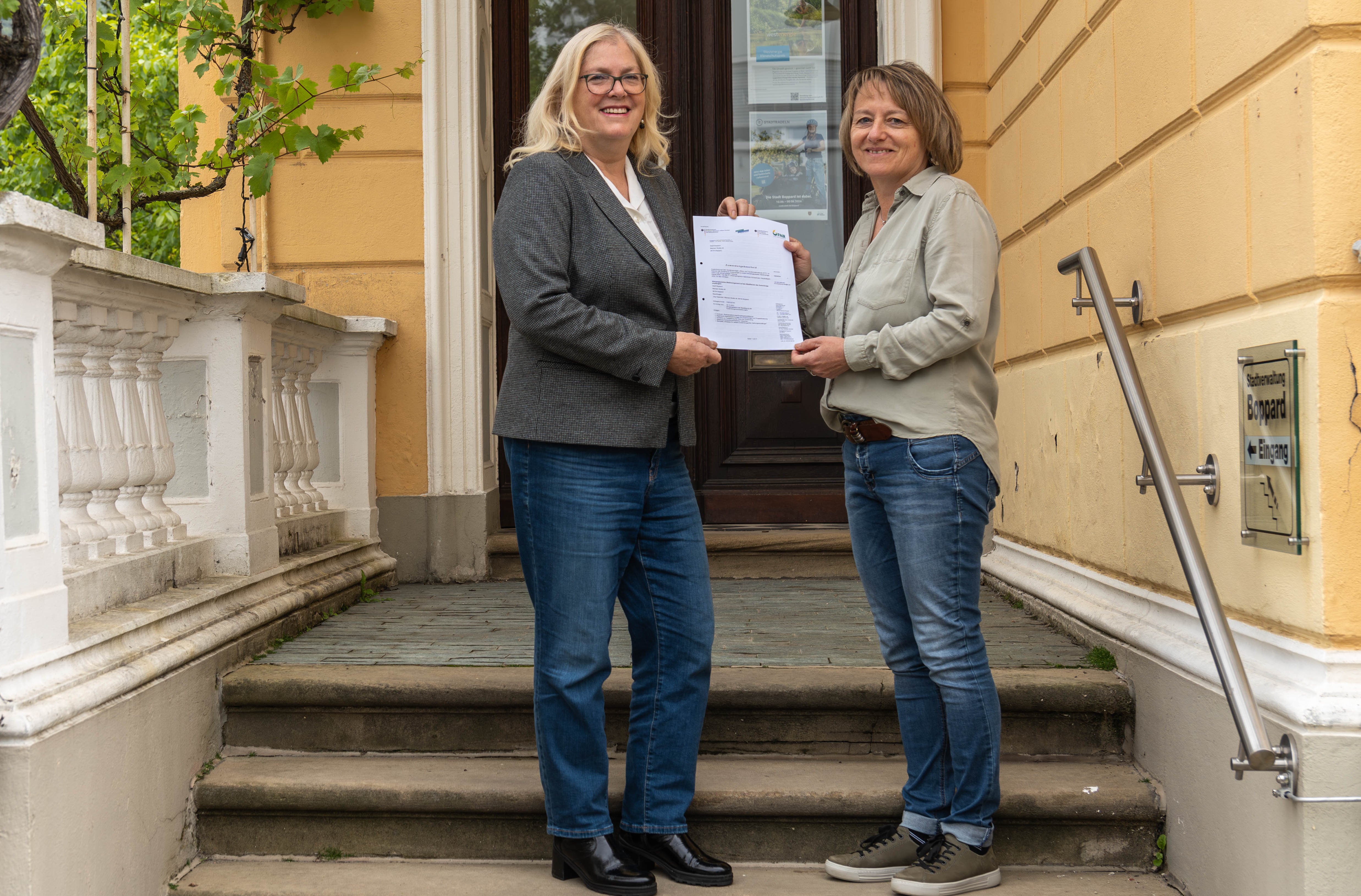 Die städtische Beigeordnete Margit Gronen (links) und Heidi König, Mitarbeiterin der Stadt Boppard, mit dem Zuwendungsbescheid über Mittel aus dem Förderprogramm für „Klimaangepasstes Waldmanagement“.