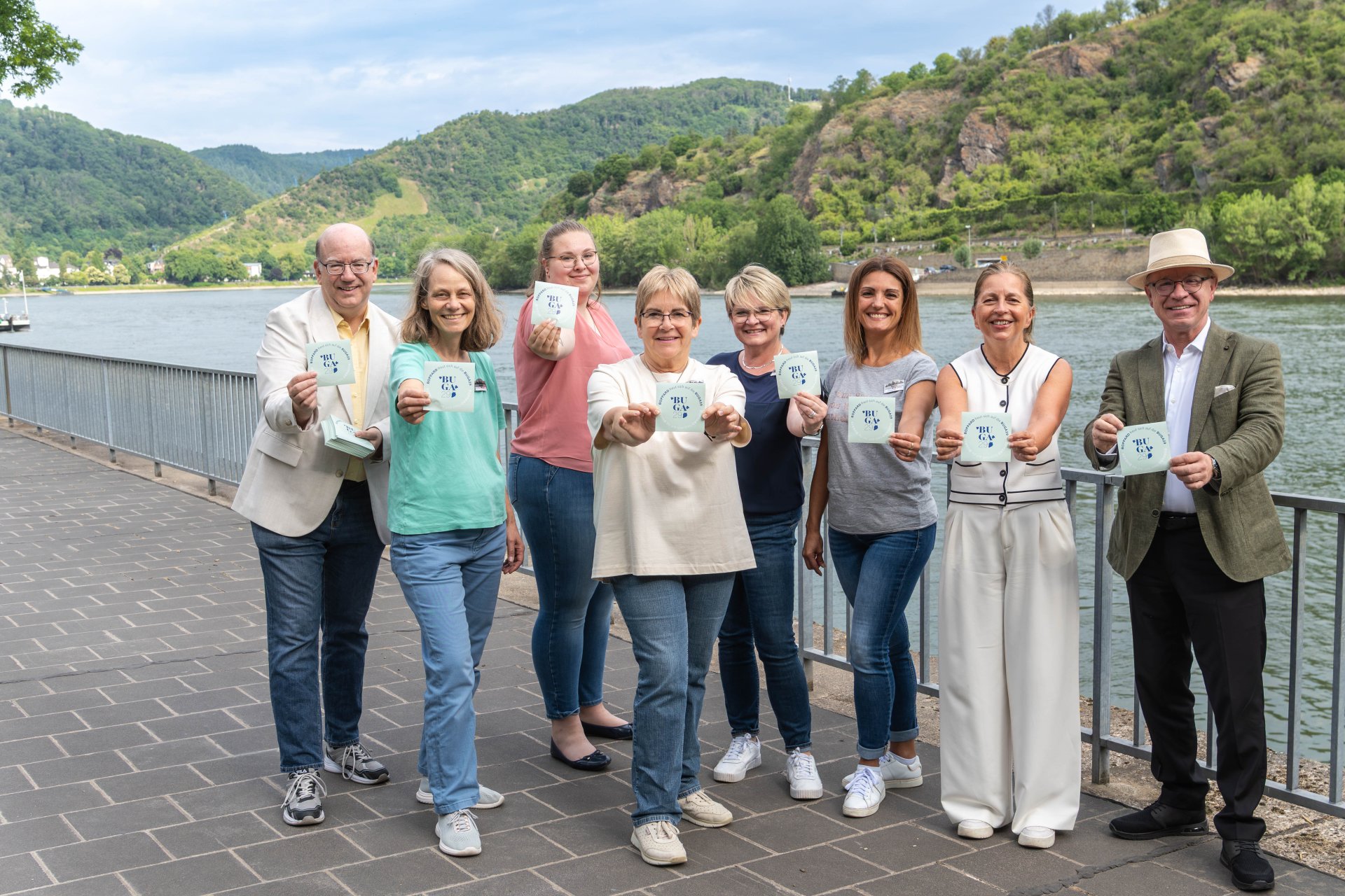 Bürgermeister Jörg Haseneier (rechts), die Vorsitzenden der Werbegemeinschaft Boppard, Nicole Weißer (2. von rechts), der Leiter der Tourist Information Boppard, Michael Defrancesco (links), und das Team der Tourist Information präsentieren das neue Bopparder Sticker-Motiv: „Boppard freut sich auf die BUGA29“. 