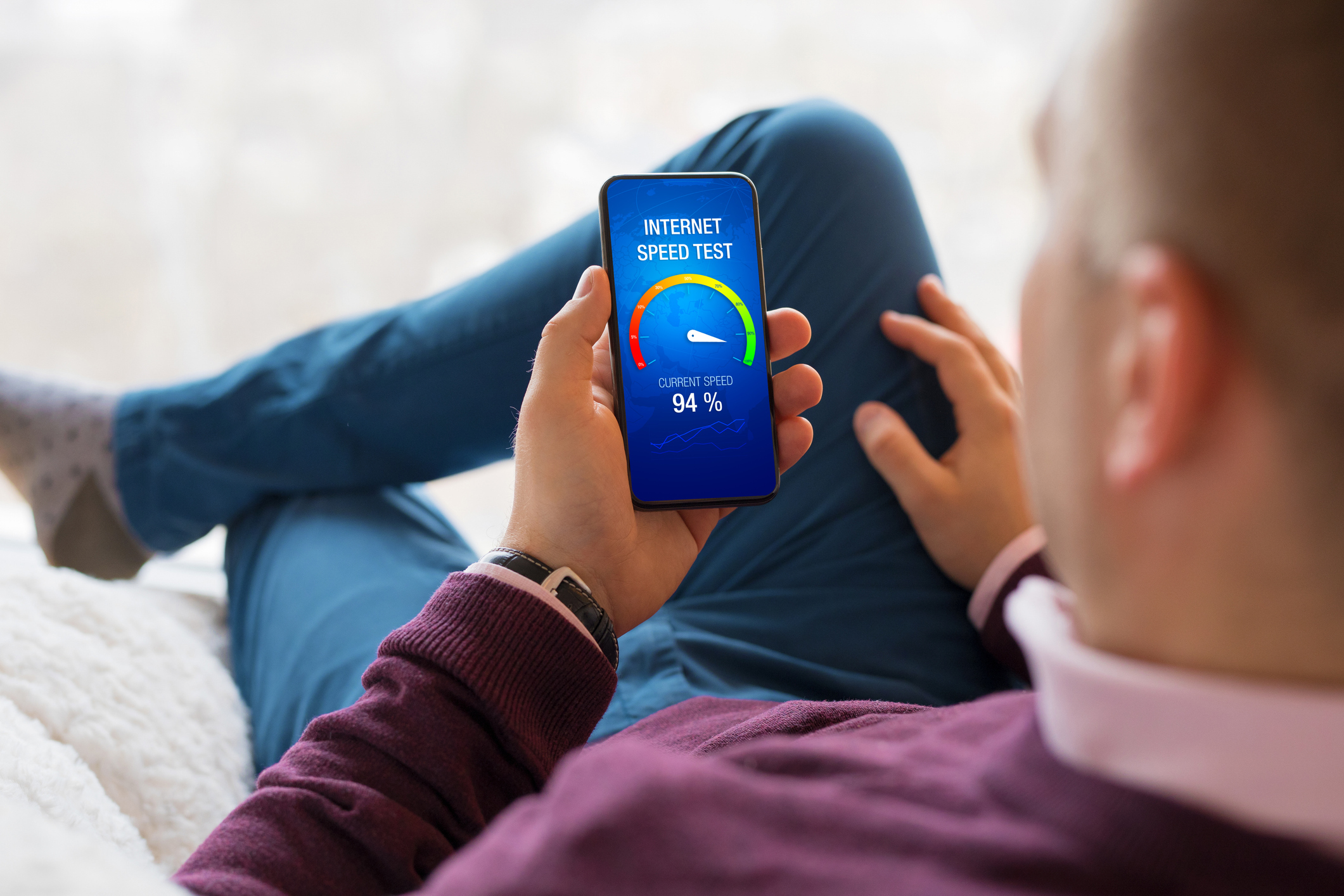Ein Mann checkt die Geschwindigkeit der Internetverbidung mit einer App auf seinem Handy.