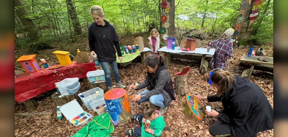Kinder und Erwachsene bemalten gemeinsam farbenfrohe Schilder und Dekorationen für die verschiedenen Waldplätze und verwandelten einfache Vogelhäuschen in kleine Kunstwerke. 